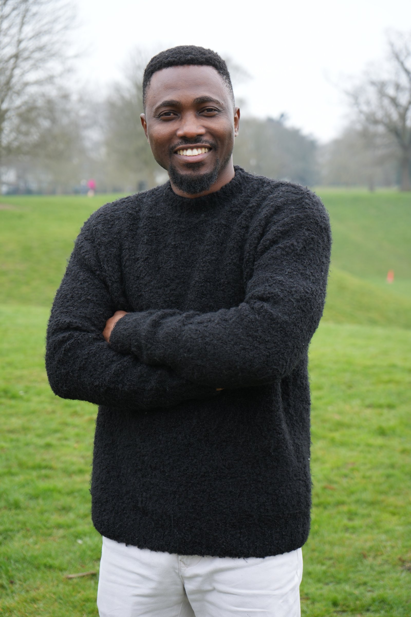 Joe Quarcoo smiling outdoors in a black jumper.